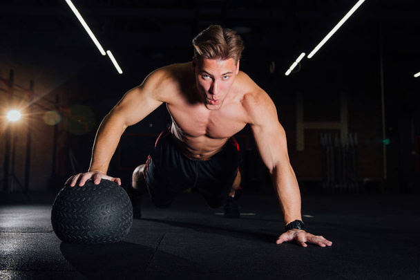 Confident muscled man doing push up from MEDICINE ball in gym. - Zdjęcie, obraz