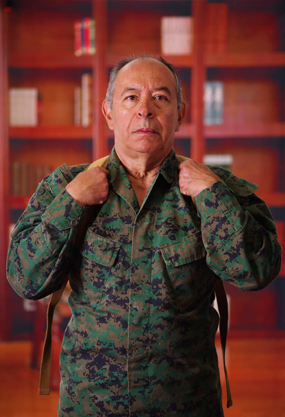 Close up of a serious veteran soldier wearing a military uniform and a backpack, in a blurred background - Photo, Image