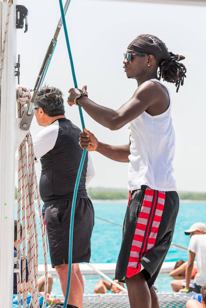 SAONA, DOMINICAN REPUBLIC - MAY 25, 2017: Black man on the yacht mast. Vertical. Close-up. - Φωτογραφία, εικόνα