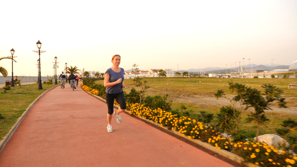 Road runner kobieta działa w parku, jogging wzdłuż gaju palmowego, Kobieta biegania na świeżym powietrzu, parku z palmami, wałowa, lato. 4 k zwolnionym tempie - Materiał filmowy, wideo