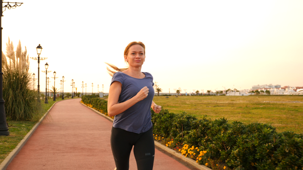 Road runner nő fut park, jogging palm grove mentén futó nő szabadban, Park, pálmafák, a töltésen, a nyáron. 4 k-lassú mozgás - Felvétel, videó