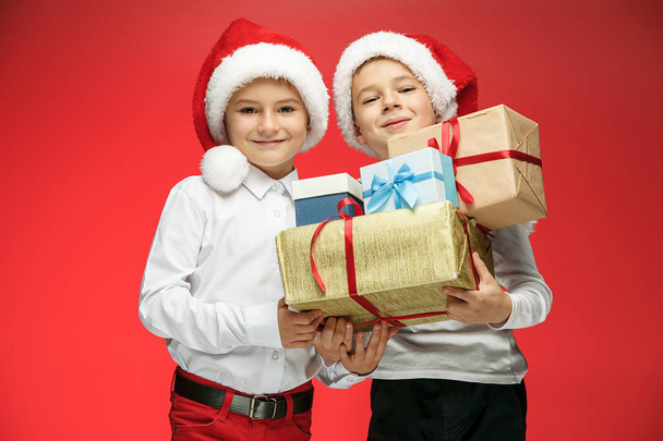 Due ragazzi felici in cappelli Babbo Natale con scatole regalo in studio
 - Foto, immagini