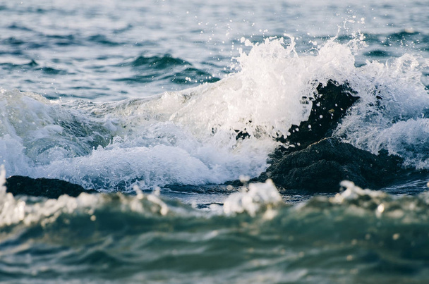 schizzi onda mentre colpisce la roccia in spiaggia
 - Foto, immagini
