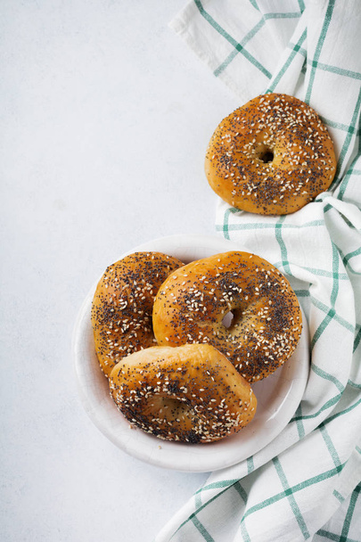 Bagels in a ceramic old bowl with a textile napkin on a light stone or concrete background.  - Foto, Imagen
