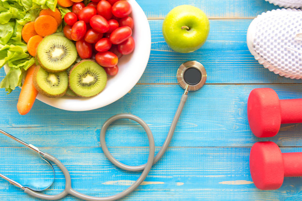 Diet and weight loss for healthy care with medical stethoscope, fitness equipment,measuring tap,fresh water and green apple on wooden background top view. - Fotografie, Obrázek