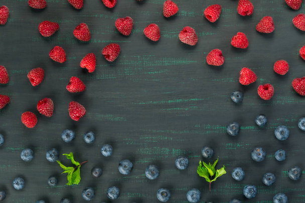 berries raspberries and blueberries lie on a black background in the middle place for inscription - Valokuva, kuva