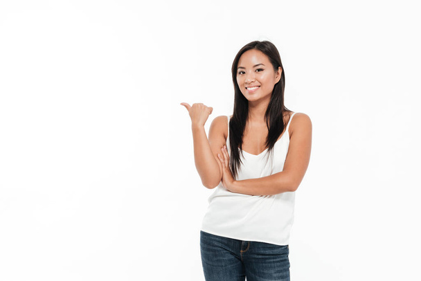 Portrait of a cheerful young asian woman pointing finger away - Foto, Bild