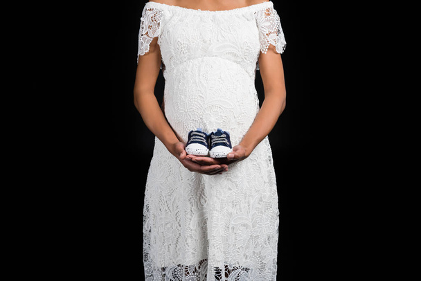 Embarazada mujer sosteniendo par de zapatos
     - Foto, imagen