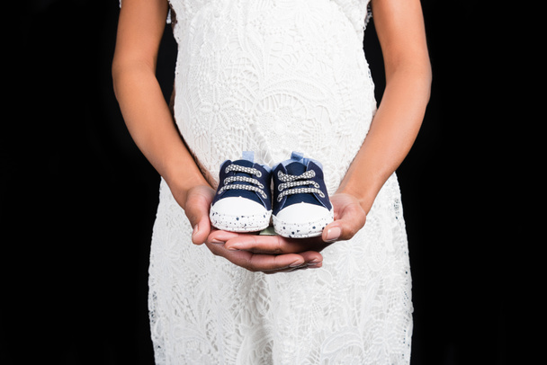 Pregnant woman holding small shoes     - Photo, Image