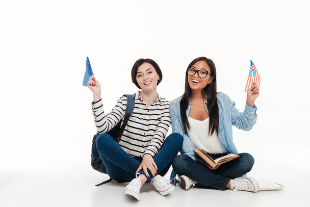 Twee jonge vrouwelijke studenten houdt ons vlaggen glimlachen - Foto, afbeelding