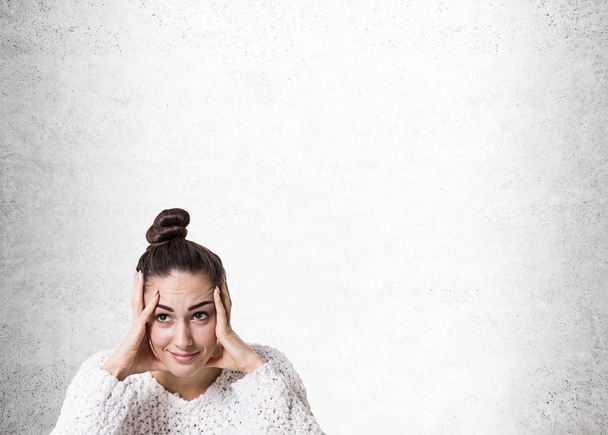 Stressed young woman with a bun, concrete - Foto, imagen