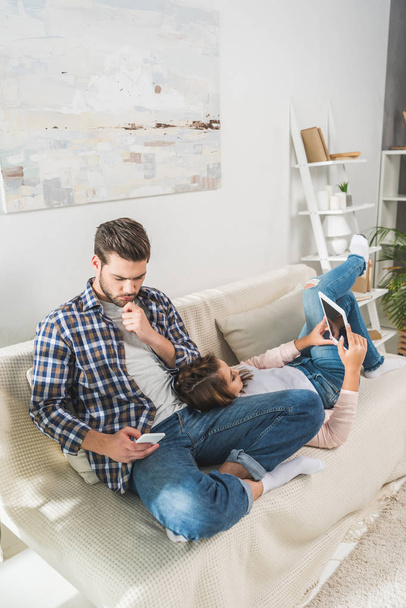 couple on sofa using devices - Foto, imagen