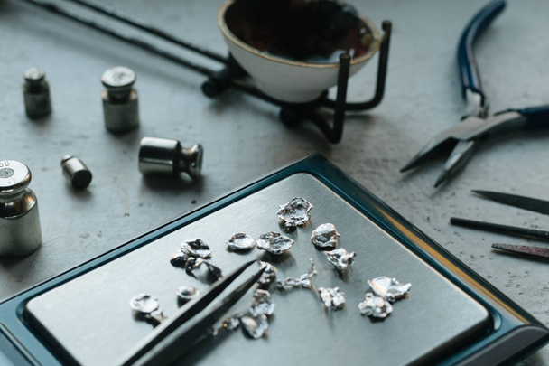 Jewelry tools. Jewellery. Goldsmith workplace, workspace on light background. Hand craft. Workshop. Manufacturing. Weigh-scales with granules of metal silver and platinum. Closeup. Toned - Foto, Bild