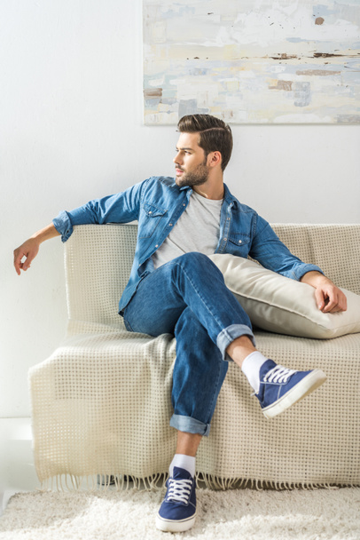 attractive man sitting on sofa - Фото, зображення