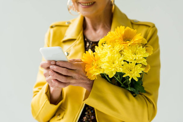 senior woman with flowers and smartphone - Φωτογραφία, εικόνα