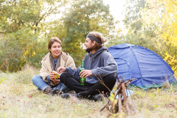 Couple relaxing in the forest. A loving couple is sitting in front of the tent. - Zdjęcie, obraz