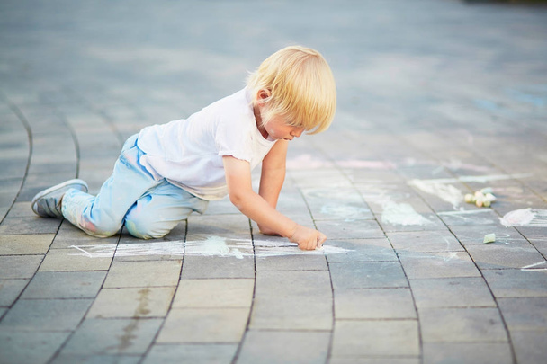 Little boy drawing with chalks on asphalt - Photo, image