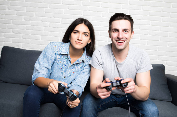 Beau couple jouant à des jeux vidéo sur console s'amusant à la maison
 - Photo, image