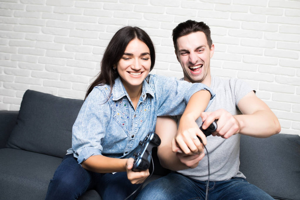 Hermosa pareja jugando videojuegos en la consola divirtiéndose en casa
 - Foto, Imagen