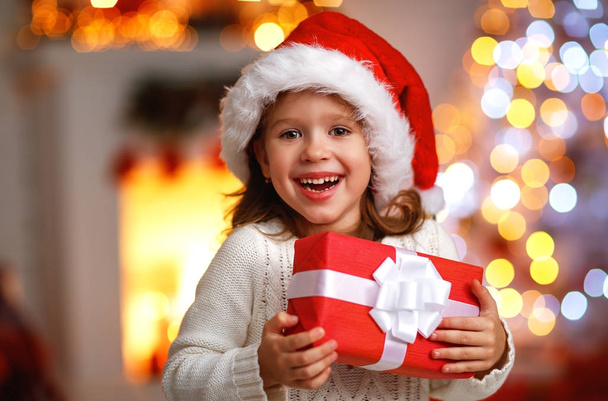 happy laughing child girl with christmas present at home - Фото, изображение