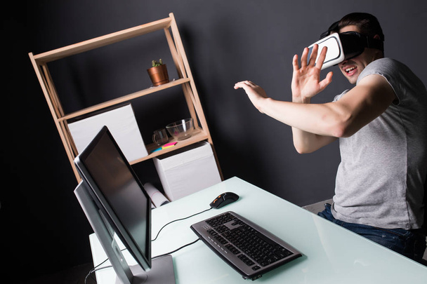 Giovane uomo sperimentando giochi con occhiali di realtà virtuale. Auricolare VR dispositivo di riproduzione su pc
 - Foto, immagini