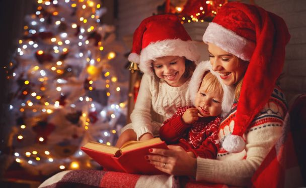 family mother and children read a book at christmas near   firep - Foto, Imagen