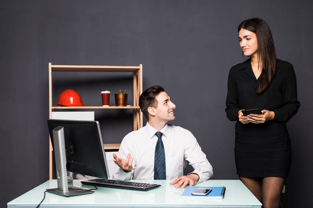 We already have great results. Young beautiful woman pointing at laptop with smile and discussing something with her coworker while standing at office - Photo, Image