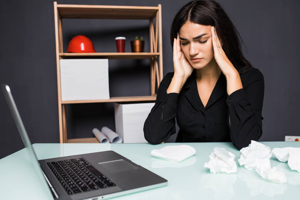 Young attractive woman at modern office desk, working on laptop, massaging temples to forget about constant headaches, noisy loud office giving a migraine, relieving stress, chronic pain, help soothe - Fotó, kép