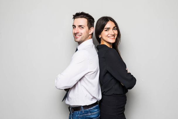 Concept de partenariat en entreprise. Jeune homme et femme debout dos à dos avec les mains croisées sur fond gris
 - Photo, image