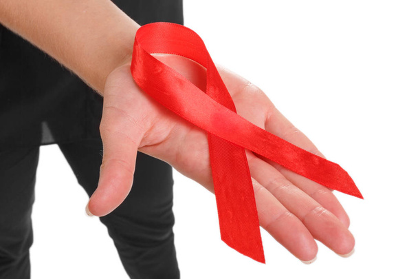 Close-up picture of a red ribbon on a female hand isolated on a white background. A symbol for the prevention of illegal drugs, drunk driving, and to stop drugs. Solidarity of people living with AIDS. - Фото, изображение