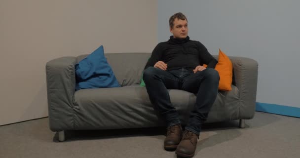 Az ember ül a kanapén, és várakozás - Felvétel, videó