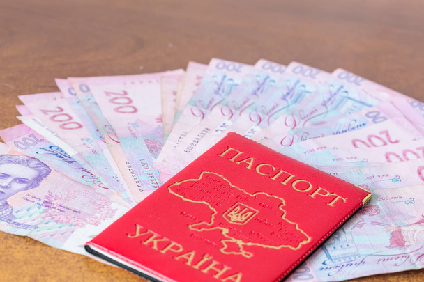 Pasaporte nacional ucraniano con hryvnias en la mesa
 - Foto, Imagen