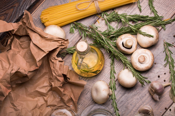 Fragrant rosemary twigs, Italian pasta and mushrooms on wooden table background. Cooking concept. - Photo, image