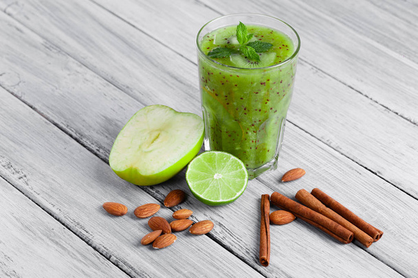 top view of glass of smoothie from kiwi, apple, and lime with mint on a gray wooden background. - Valokuva, kuva