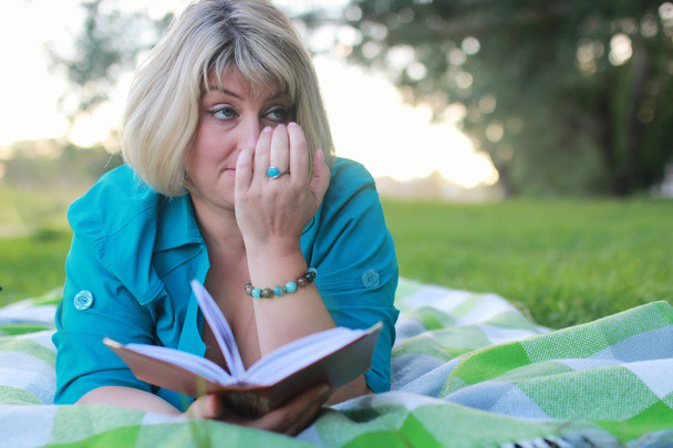 жінка в парку з книгою на траві
 - Фото, зображення