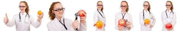 Pretty female doctor with stethoscope and orange isolated on whi - Photo, Image