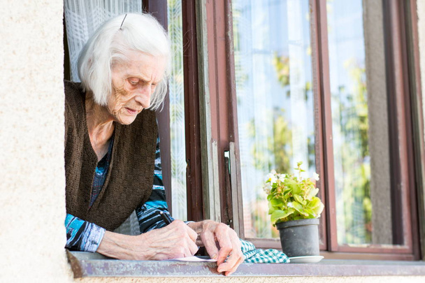 Mujer mayor firma cheque de jubilación en casa
 - Foto, imagen
