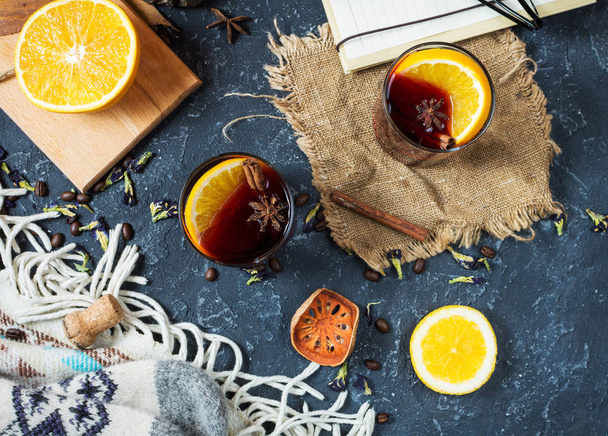 The concept of homemade mulled wine. Mulled wine in a glass on a dark stone background. - Photo, image