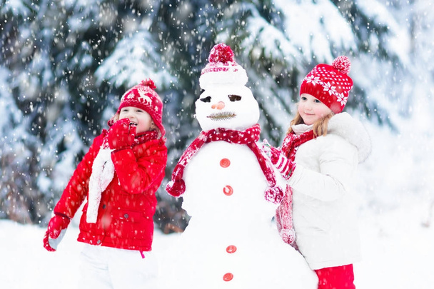 Crianças a construir boneco de neve. Crianças na neve. Diversão de inverno
. - Foto, Imagem