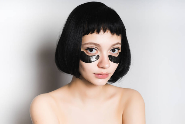 young beautiful girl with black short hair, under the eyes black silicone patches - Foto, Imagen