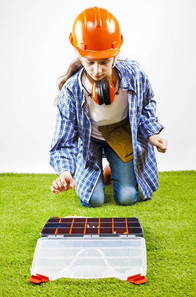 A young female construction worker chooses a tool for work in a box. Building concept - Foto, afbeelding