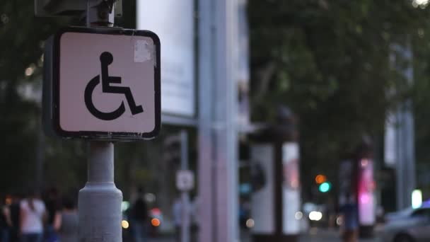 Znak z osobą niepełnosprawną, siedząc na wózku inwalidzkim na tle niewyraźne pieszych ludzi. Koncepcja - Materiał filmowy, wideo