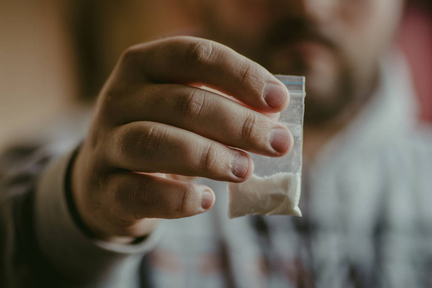 Дилер наркотиків, що дає або продає пакет з героїном, кокаїном або іншим порошковим наркотиком, вибірковий фокус на руці з наркотиками
 - Фото, зображення