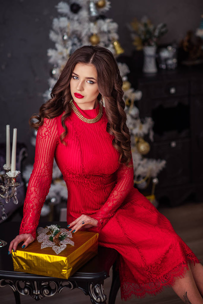 A girl in a red dress unpacks presents - 写真・画像