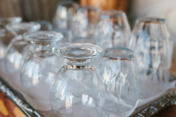 Clean glass goblets are turned upside down and stand on tray in cafe - Photo, Image