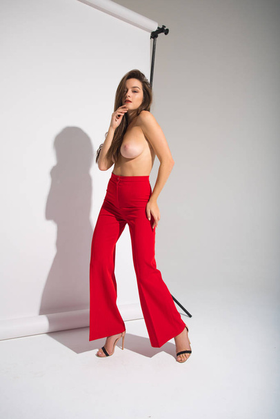bella nudo donna in rosso pantaloni posa casting ombra isolato su il grigio sfondo
 - Foto, immagini