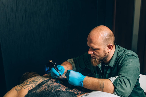 master καλλιτέχνης τατουάζ κάνει μια δερματοστιξία. Κινηματογράφηση σε πρώτο πλάνο - Φωτογραφία, εικόνα