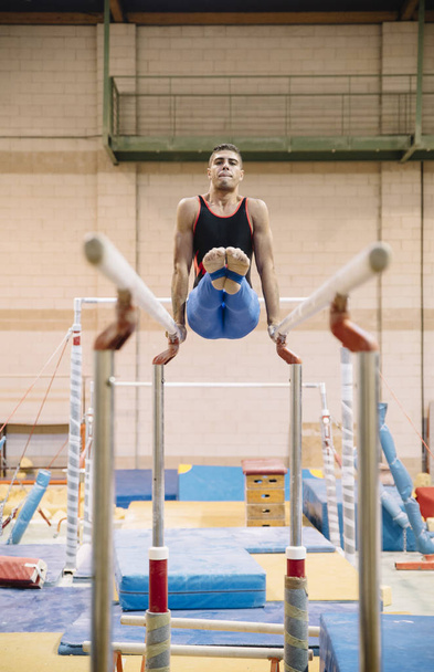 Male gymnast performing on gymnastic rings - Фото, изображение