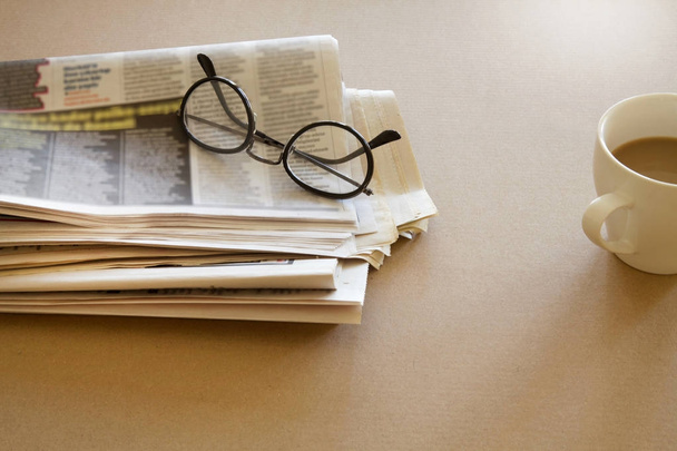 Newspaper with eyeglasses on brown background - 写真・画像