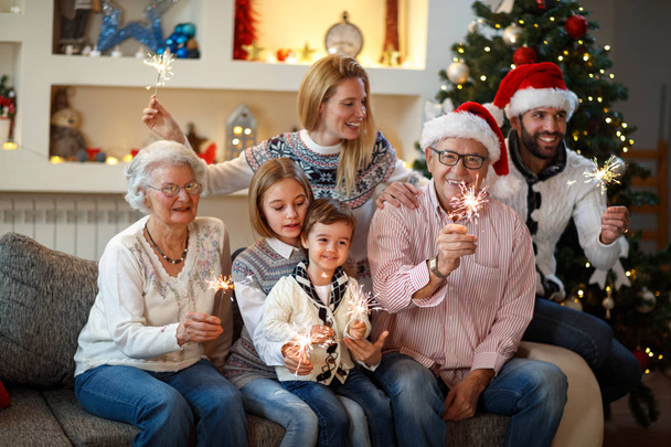 Avós com filhos cintilantes com brilhos de Natal
 - Foto, Imagem